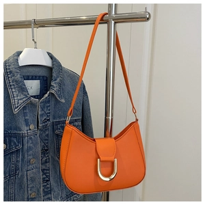 Detail of a bright orange crescent shoulder bag with golden D-ring buckle on denim jacket