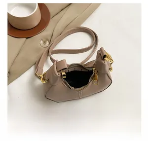 Detail view of mini beige crossbody bag interior space with golden zipper and PU leather