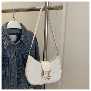 Detail of white hobo bag with gold horseshoe buckle hanging on metal hanger