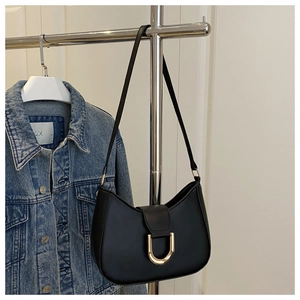 Detail view of black crescent underarm bag featuring a golden D-ring buckle and slim strap