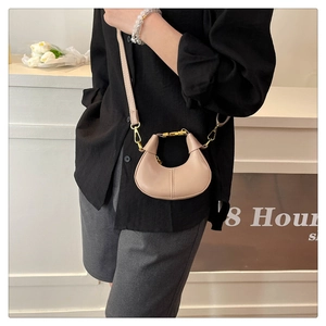 Detail of a beige half-moon crossbody bag in smooth faux leather with golden hardware