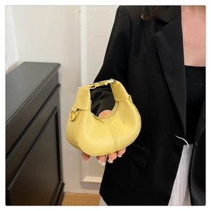 Close-up of bright yellow hobo bag with sleek gold hardware and leather texture