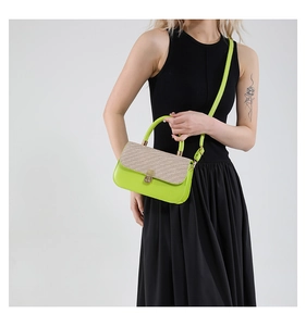 Detail of neon green leather handbag with beige straw texture and gold clasp