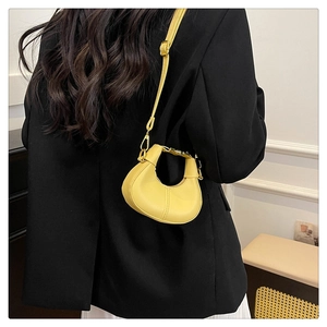 Lemon yellow crescent bag styled over a black blazer and white skirt for a modern commute