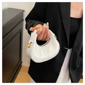 Detail of white glossy crescent bag with gold D-ring hardware and zipper closure