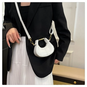 Mini white dumpling shoulder bag styled with black blazer and gold metal hardware