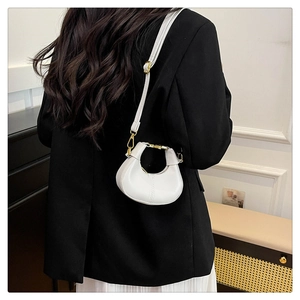 Back view of a model wearing a white crescent mini crossbody bag over a black blazer