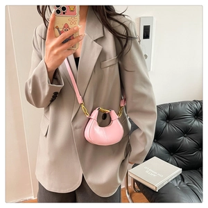 Mirror selfie showing a mini pink crescent crossbody bag styled with casual outfit