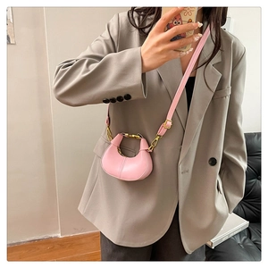 Close-up of a pink crescent leather handbag with gold hardware on a gray blazer model