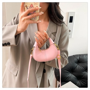 Mirror selfie showing the pink mini crescent bag with gold chain and crossbody strap