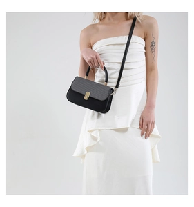 Detail of two-tone crossbody bag with grey woven texture and golden twist-lock closure