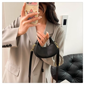 Close-up of black leather micro crescent bag with gold hardware and removable shoulder strap