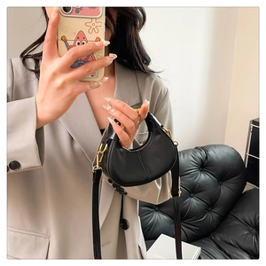 Detail of black matte leather dumpling bag with gold metal buckle and thin shoulder strap