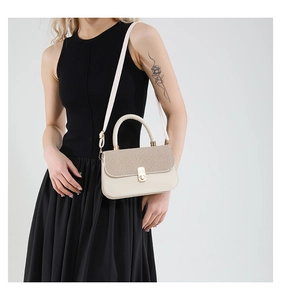 Close-up of beige crossbody bag with textured woven flap and golden twist lock