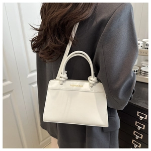 Detail of white leather handbag with knot handle and golden Fashion Bag logo on front