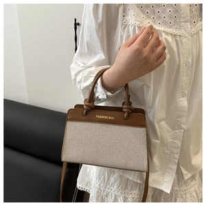 Canvas and leather handbag detail showing the unique knotted handle and fashion bag print