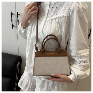 Detail of vintage beige knit and brown leather tote bag held by model in lace dress