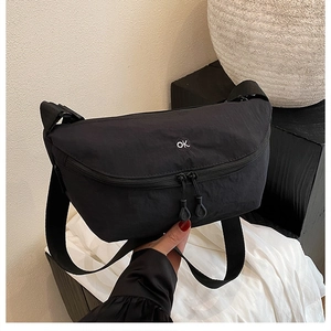 Détail du sac bandoulière en nylon noir avec broderie ok blanche et double fermeture