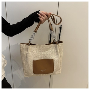 Detail of woven tote bag with brown leather pocket and elegant silver chain strap