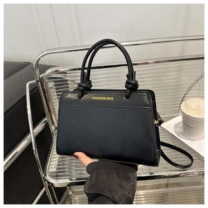 Close-up of black PU leather handbag featuring Fashion Bag text and curved handles