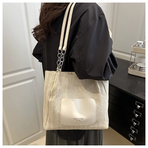 Detail view of woven cream tote bag featuring a leather pocket and thin shoulder straps