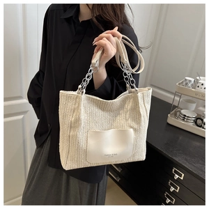 Detail of herringbone woven texture and faux leather pocket on cream tote bag