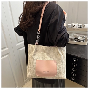 Detail of woven straw tote bag featuring pink PU leather pocket and metal chain strap