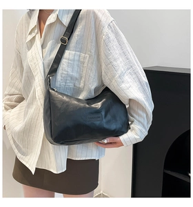 Close-up of black leather shoulder bag with Fashion logo and gold strap buckle
