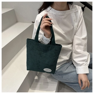 Detailed view of dark green corduroy tote bag with texture and brand logo label