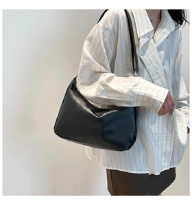 Detailed view of black faux leather crescent shoulder bag with embossed Fashion tag