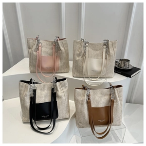 Detail view of woven straw tote bags in pink, white, black, and brown with chain straps