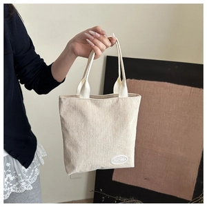 Detail of cream corduroy tote bag featuring soft ribbed texture and FANYISSA label