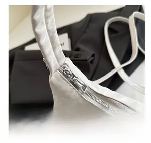 Nahaufnahme eines glatten silbernen Metallreißverschlusses an weißer Lederhandtasche