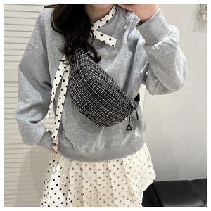 Close-up of black and white checkered tweed waist bag with a triangle zipper detail