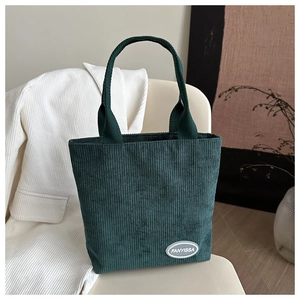 Detailed texture of dark green corduroy tote bag with vintage FANYISSA brand patch