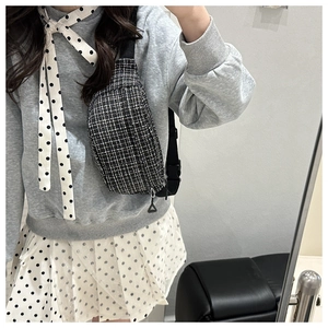 Detail showing the black and white tweed texture and adjustable strap of this crossbody bag