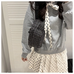 Detail of tweed crossbody chest bag with black and white plaid pattern on model