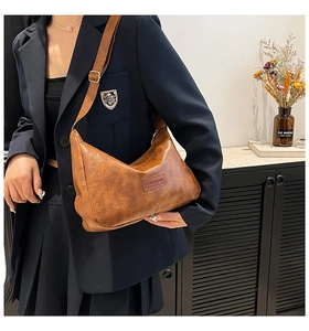 Close-up of vintage brown PU leather pillow bag with fashion tag and metal buckle detail