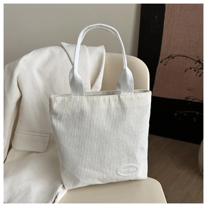 Close-up of white corduroy tote bag texture with fabric handles and FANYISSA logo