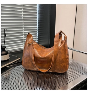 Detail of vintage brown textured leather bag with FASHION label and wide shoulder strap