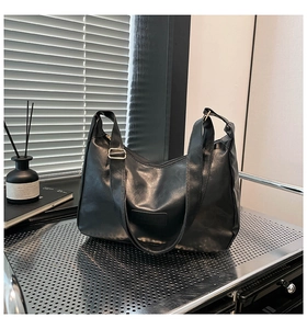 Detail showing soft black pleated leather texture and wide strap of this tote bag