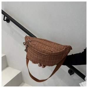 Detail of brown plaid textured sling bag with adjustable canvas strap and double zipper