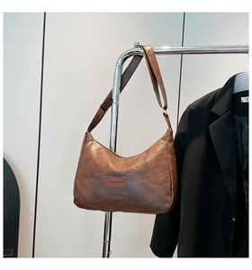 Detail of a brown crescent hobo bag in wrinkled PU leather with a fashion patch