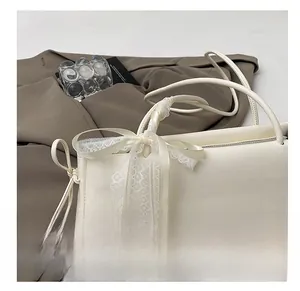 Detail of a creamy white leather shoulder bag with decorative lace scarf and top zipper
