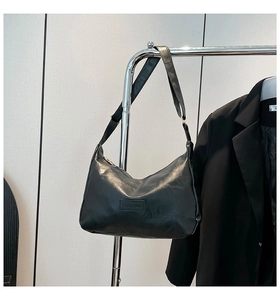 Detail of black oil wax leather hobo bag featuring fashion embossed plate and gold hardware