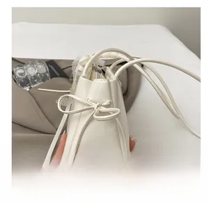 Detail shot of the white matte leather shoulder bag with chic side bow and drawstring strap
