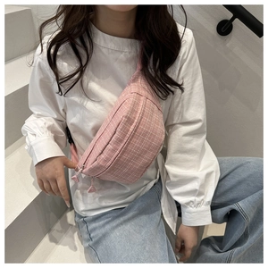 Detailed view of pink plaid crossbody bag with dual zippers on casual white shirt