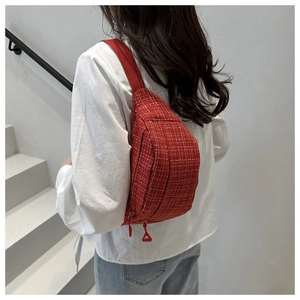 Detail of red tweed belt bag with gold thread on model in white shirt and jeans