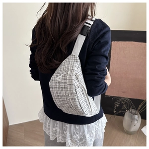Detail of tweed checkered crossbody bag featuring white nylon strap and dual zippers