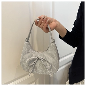 Detailansicht der silbernen Handtasche mit Schleife, Faltenstruktur und Halbmondform